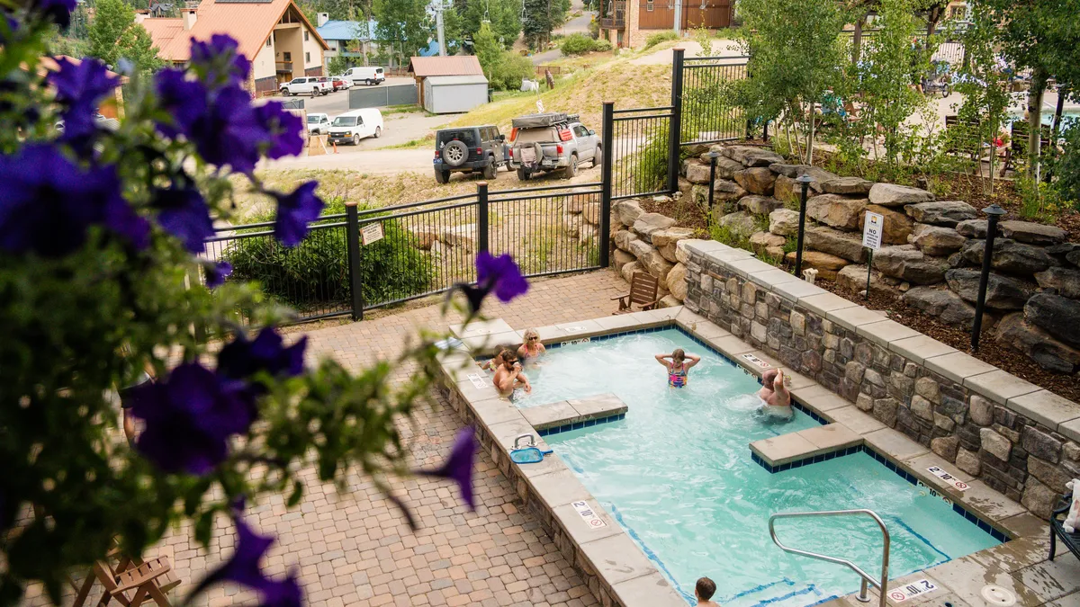 An inviting outdoor swimming pool surrounded by vibrant flowers, with guests enjoying swim and relaxation. The setting exudes a playful and cheerful mood, ideal for both family fun and tranquil lounging, and showcases the resort-style pool environment.