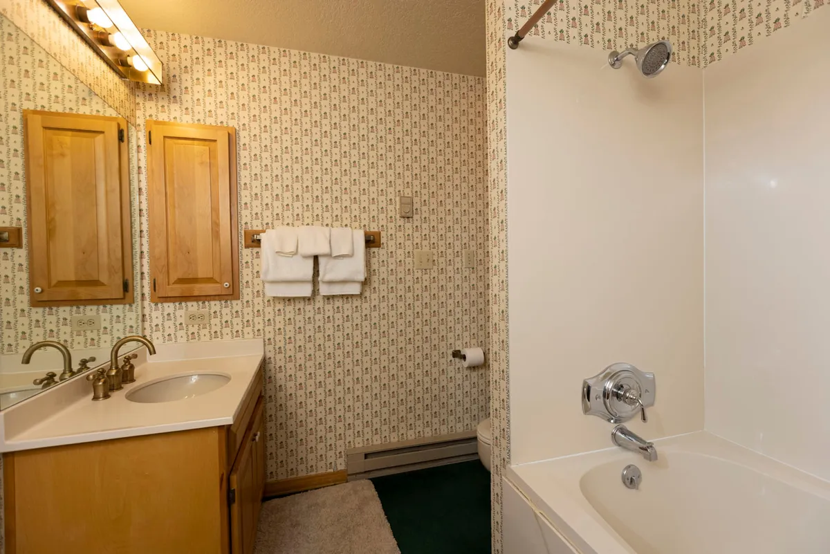 A well-appointed bathroom with a modern vanity, mirrored cabinet, and a bathtub perfect for soaking. The space feels functional yet inviting, offering comfort for daily routines or a soothing bath after outdoor activities.
